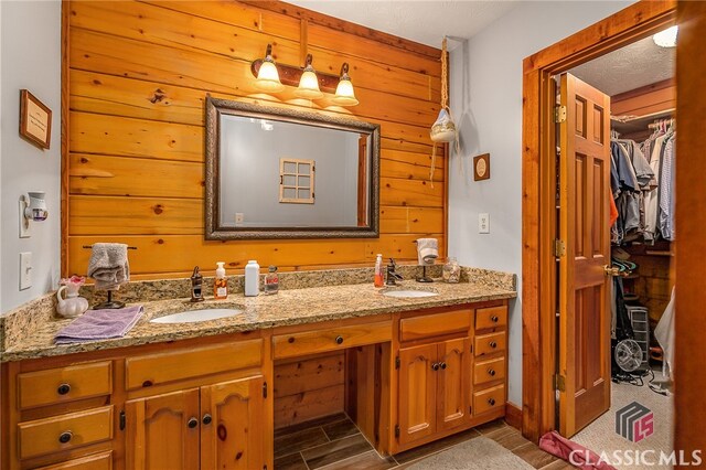 bathroom featuring hardwood / wood-style flooring, wooden walls, and vanity