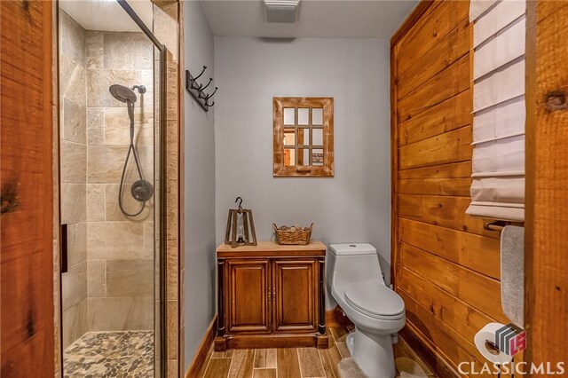 bathroom with toilet, hardwood / wood-style floors, and a shower with door