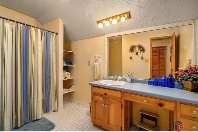 bathroom with a textured ceiling, vanity, tile patterned flooring, and lofted ceiling