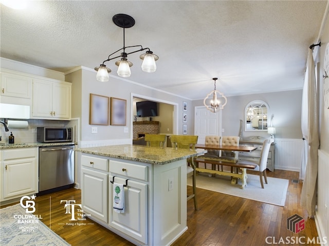 kitchen featuring appliances with stainless steel finishes, dark hardwood / wood-style flooring, decorative light fixtures, and white cabinetry