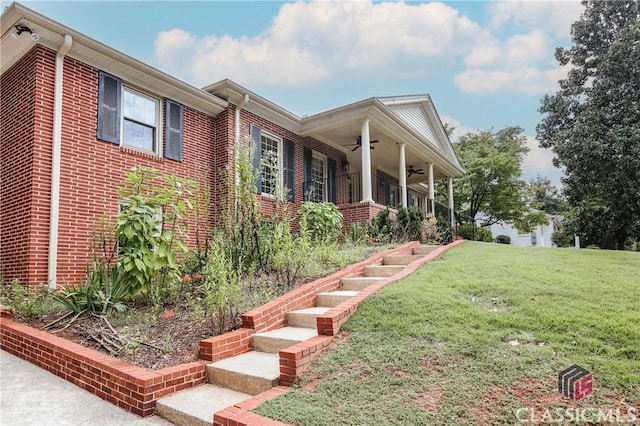 view of home's exterior featuring stairs, a yard, brick siding, and a ceiling fan