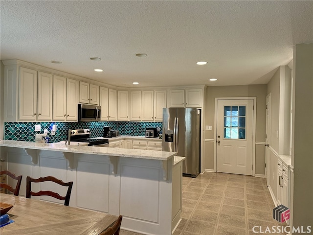 kitchen featuring a kitchen breakfast bar, appliances with stainless steel finishes, and kitchen peninsula