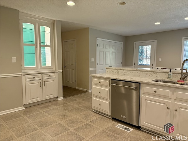 kitchen with white cabinets, light stone countertops, stainless steel dishwasher, and sink