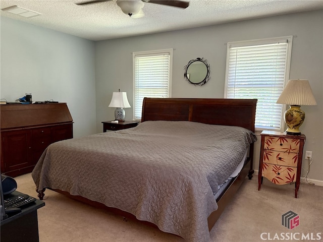 bedroom featuring light carpet, multiple windows, a textured ceiling, and ceiling fan