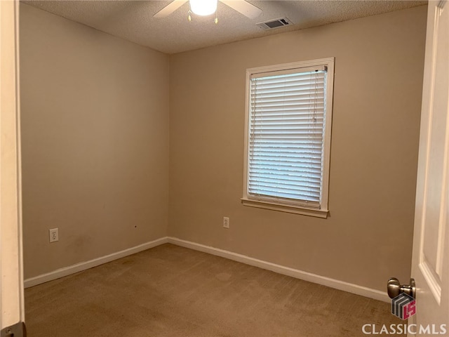 carpeted spare room featuring ceiling fan and a textured ceiling