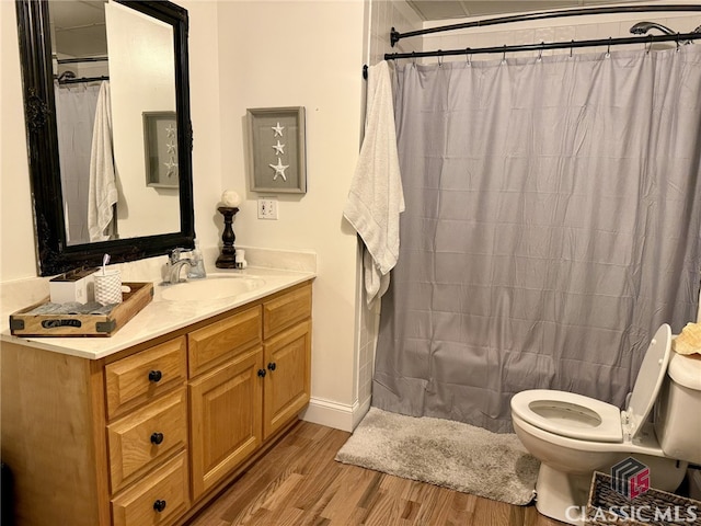 bathroom featuring toilet, hardwood / wood-style floors, curtained shower, and vanity