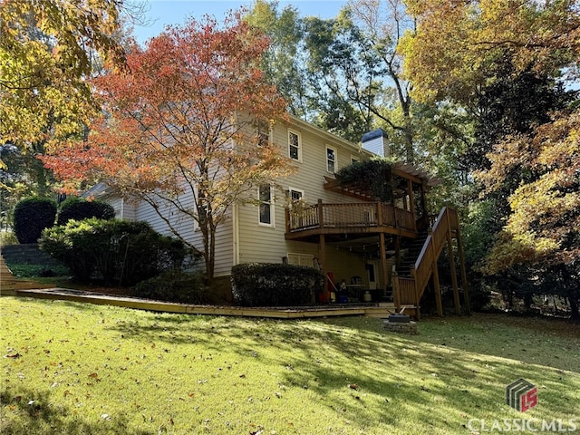 rear view of property featuring a wooden deck and a lawn