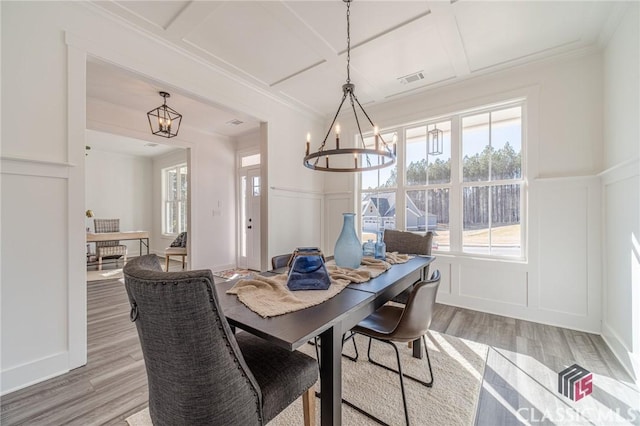 dining space featuring crown molding, coffered ceiling, a chandelier, and hardwood / wood-style floors