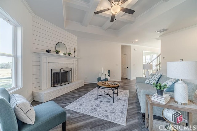 living room with ceiling fan, dark hardwood / wood-style floors, a brick fireplace, beam ceiling, and coffered ceiling