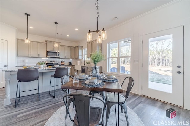 dining space with dark wood-type flooring, sink, and ornamental molding