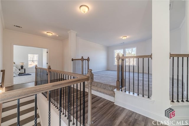 hall featuring ornate columns, dark wood-type flooring, and crown molding