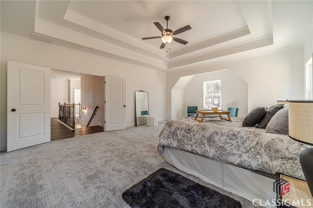 carpeted bedroom featuring ceiling fan, ornamental molding, and a tray ceiling