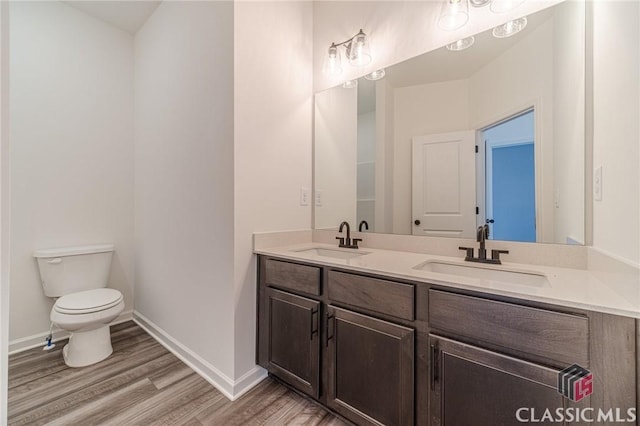 bathroom with toilet, hardwood / wood-style floors, and vanity