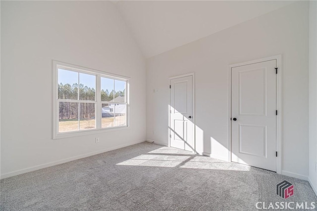 carpeted empty room with high vaulted ceiling