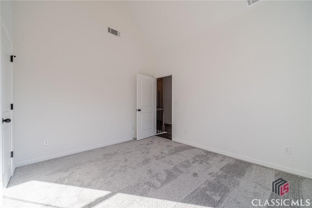 unfurnished room with light colored carpet and a high ceiling