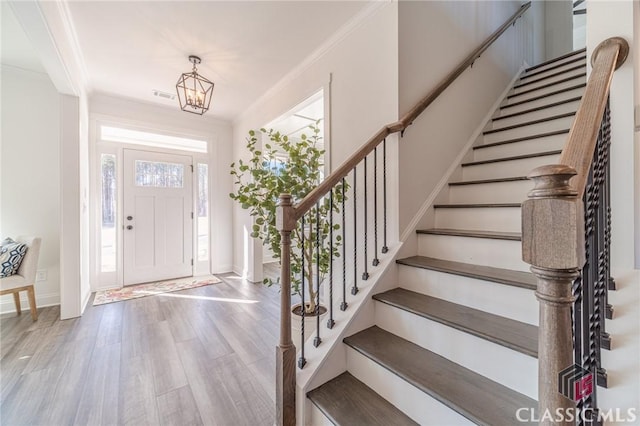 foyer entrance featuring ornamental molding, a chandelier, and hardwood / wood-style floors