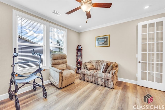 living room with ornamental molding, ceiling fan, and light hardwood / wood-style floors