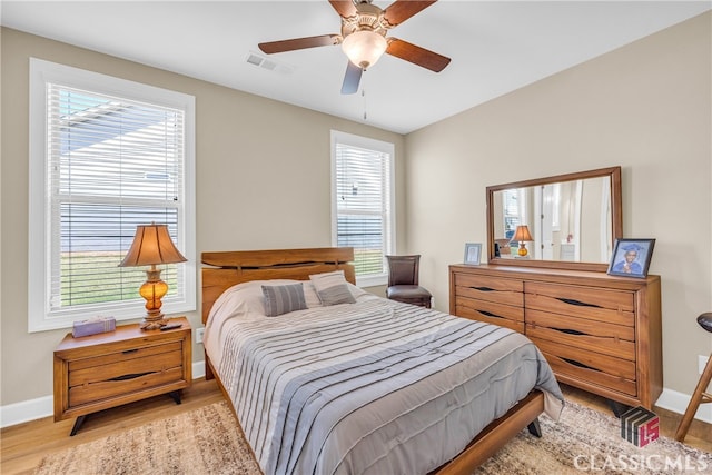 bedroom featuring light wood-type flooring, multiple windows, and ceiling fan