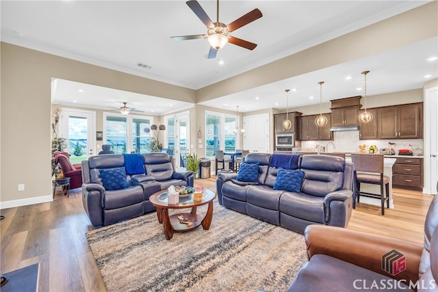 living room featuring light wood-type flooring, ornamental molding, and ceiling fan