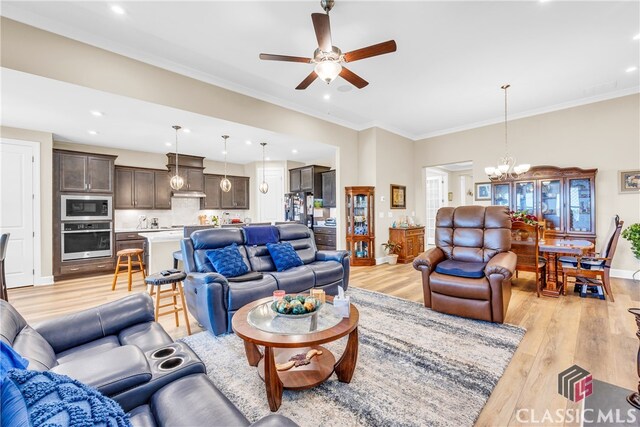 living room with crown molding, ceiling fan with notable chandelier, and light wood-type flooring