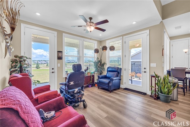 living room featuring ceiling fan, ornamental molding, light hardwood / wood-style floors, and a healthy amount of sunlight