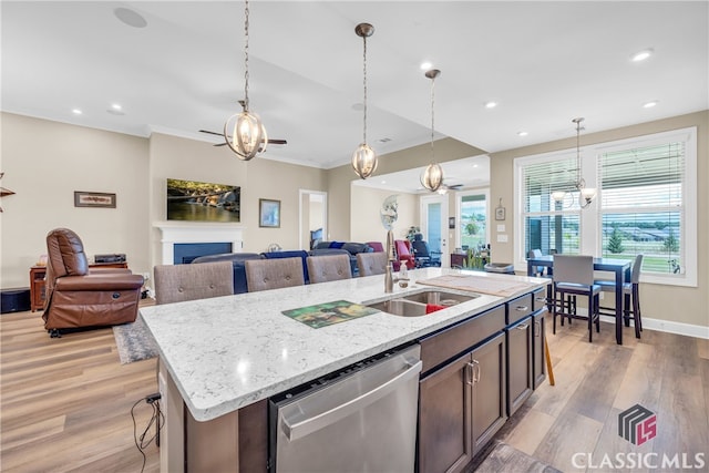 kitchen with a center island with sink, stainless steel dishwasher, plenty of natural light, and light wood-type flooring