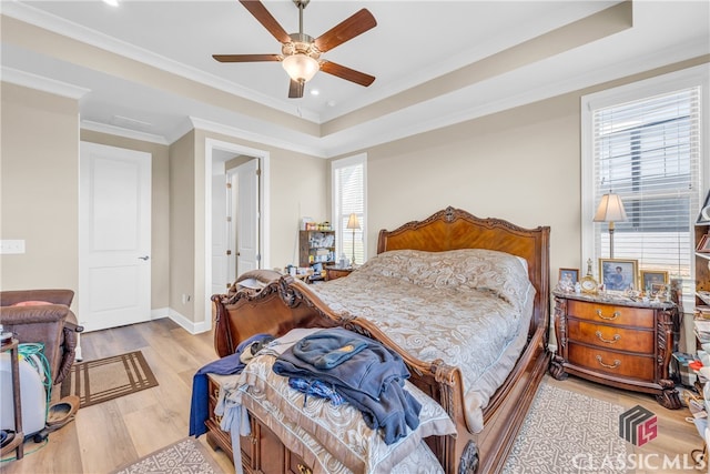 bedroom with crown molding, a tray ceiling, ceiling fan, and light hardwood / wood-style floors