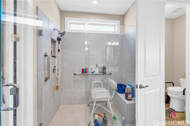 bathroom featuring a shower with door and toilet