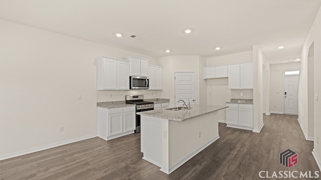 kitchen with light stone countertops, an island with sink, dark wood-type flooring, stainless steel appliances, and white cabinets