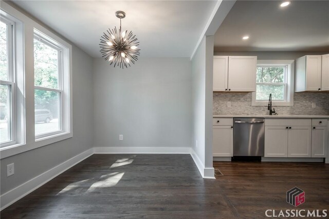 kitchen featuring stainless steel dishwasher, white cabinets, plenty of natural light, and decorative light fixtures