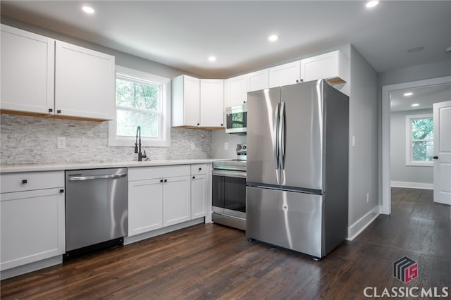 kitchen featuring appliances with stainless steel finishes, backsplash, dark hardwood / wood-style flooring, and white cabinets