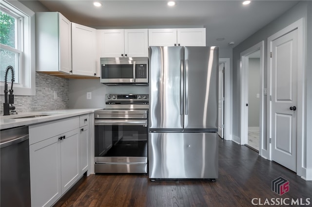 kitchen with tasteful backsplash, dark wood-type flooring, stainless steel appliances, and white cabinets