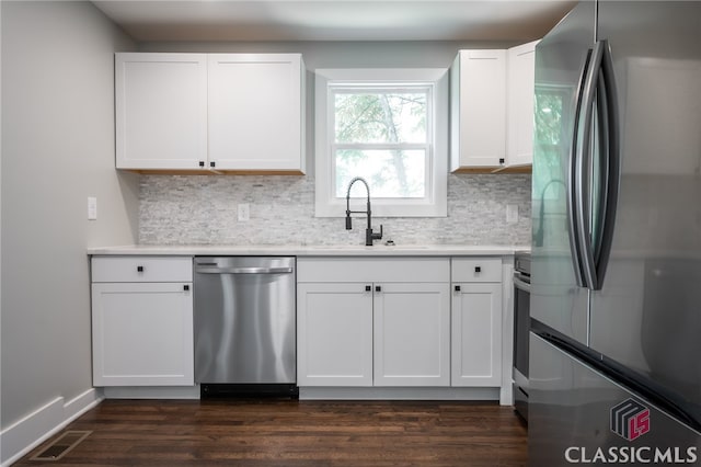 kitchen with white cabinets, stainless steel appliances, dark hardwood / wood-style floors, and tasteful backsplash