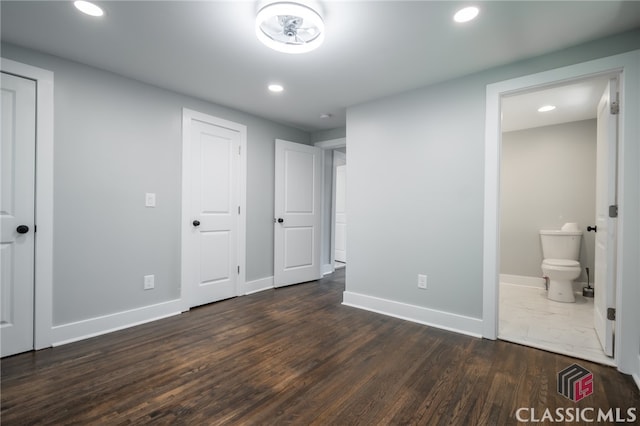 unfurnished bedroom featuring ensuite bath and dark wood-type flooring