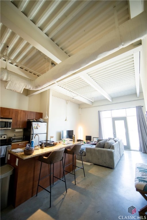 interior space with beamed ceiling, a kitchen bar, white fridge, and electric range