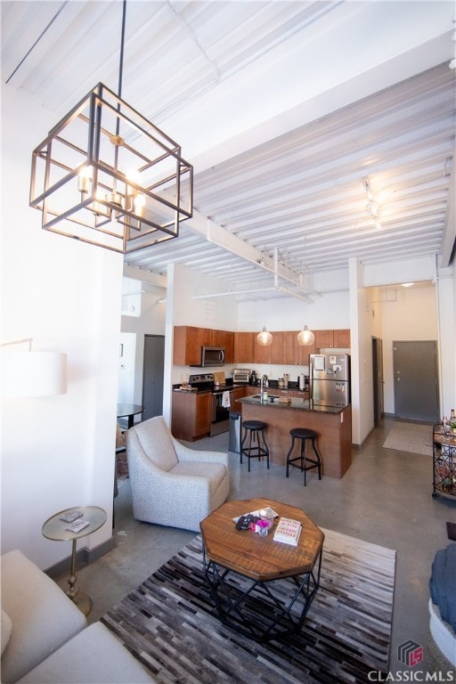 living room featuring sink, a chandelier, and concrete floors