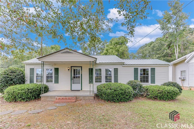 view of front of house featuring cooling unit, covered porch, and a front yard