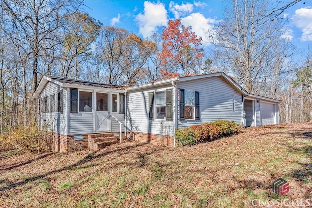 view of front of home featuring a sunroom, a garage, and a front yard