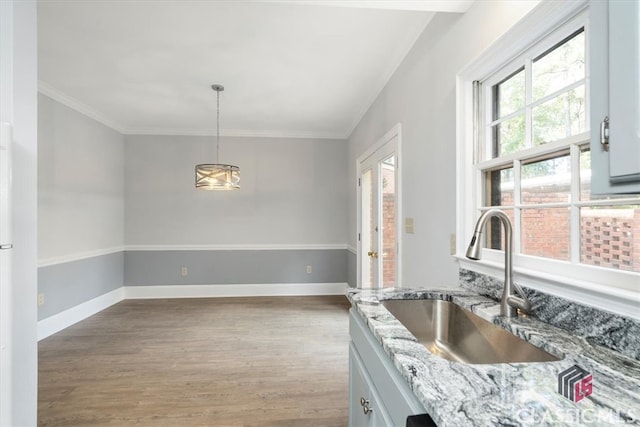 kitchen featuring white cabinetry, a wealth of natural light, light stone counters, and decorative light fixtures