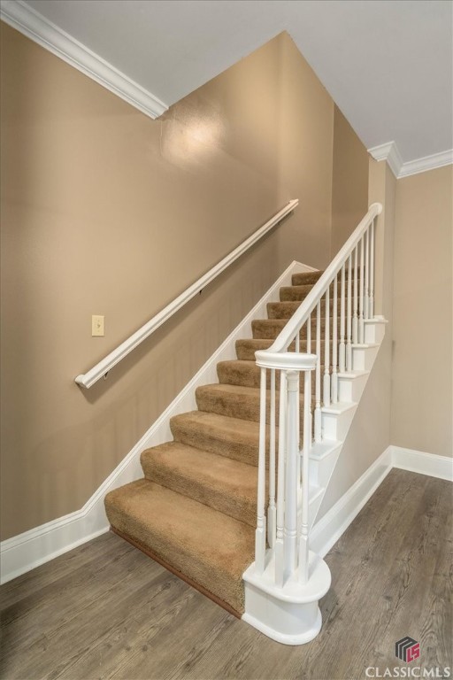 stairs with wood-type flooring and ornamental molding