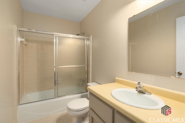 full bathroom featuring tile patterned floors, vanity, toilet, and bath / shower combo with glass door