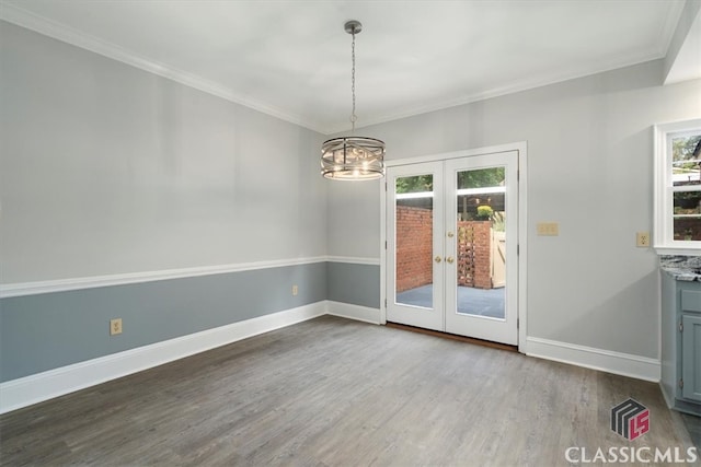 unfurnished dining area with crown molding, french doors, an inviting chandelier, and hardwood / wood-style flooring