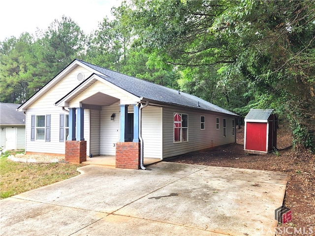 view of front facade featuring a storage shed, a shingled roof, and an outbuilding