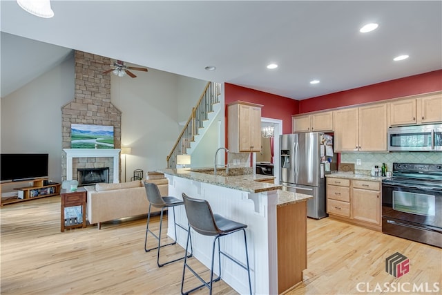 kitchen featuring light hardwood / wood-style flooring, light stone counters, light brown cabinets, and appliances with stainless steel finishes