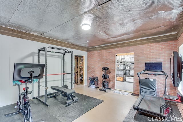 exercise room with concrete flooring and brick wall