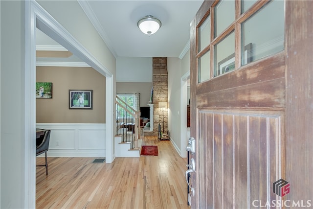 foyer entrance with ornamental molding and light hardwood / wood-style flooring