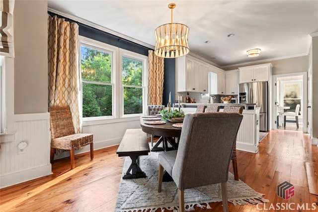 dining area featuring light wood-type flooring, crown molding, an inviting chandelier, and sink