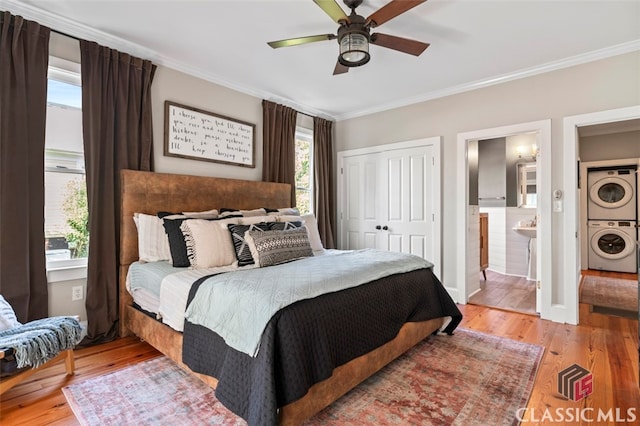 bedroom with light hardwood / wood-style flooring, multiple windows, stacked washer / drying machine, and ceiling fan