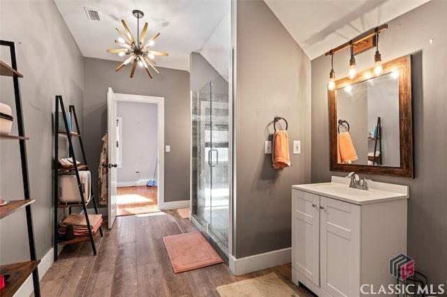 bathroom with hardwood / wood-style flooring, an enclosed shower, vaulted ceiling, an inviting chandelier, and vanity