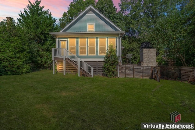 back house at dusk featuring a lawn